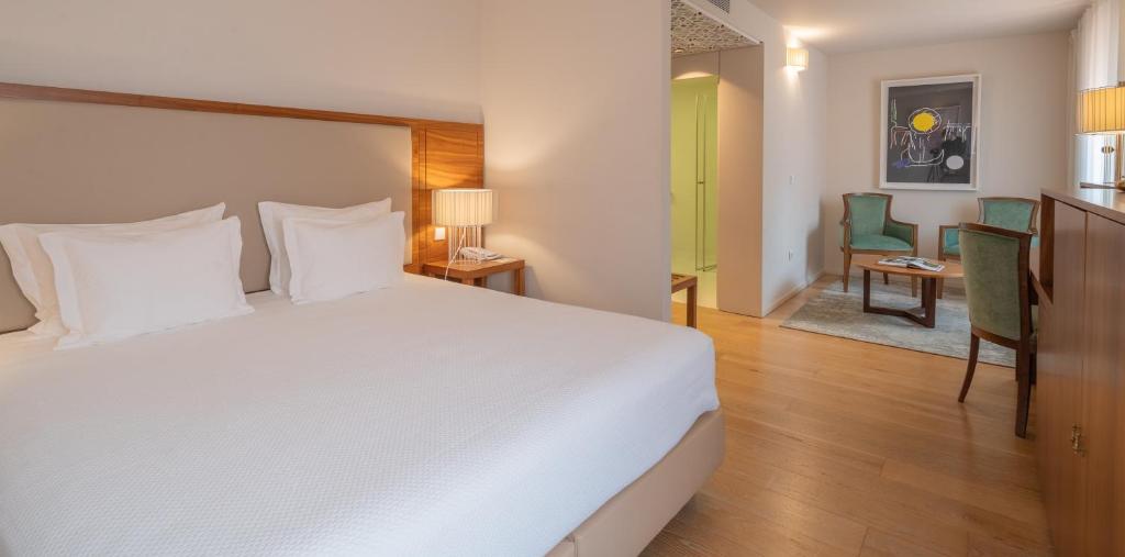 a bedroom with a large white bed and a desk at Burgus Tribute & Design Hotel in Braga