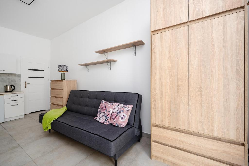 a black couch in a room with a kitchen at Łódź Urban Serenity Studio #11 by BookingHost in Łódź