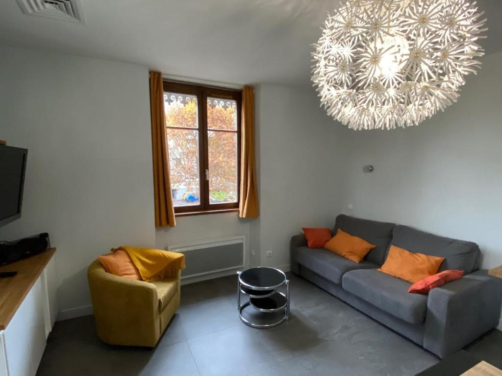 L'Ecrin de Verdure du Centre Ville في إيكس لي بان: غرفة معيشة مع أريكة وثريا