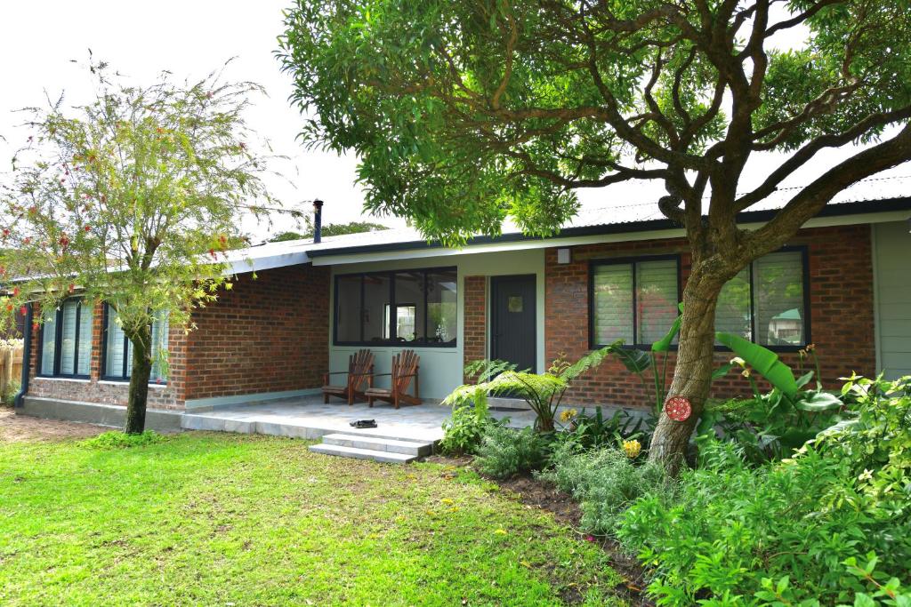 a brick house with a porch and a tree at sunbird cottage in Sedgefield