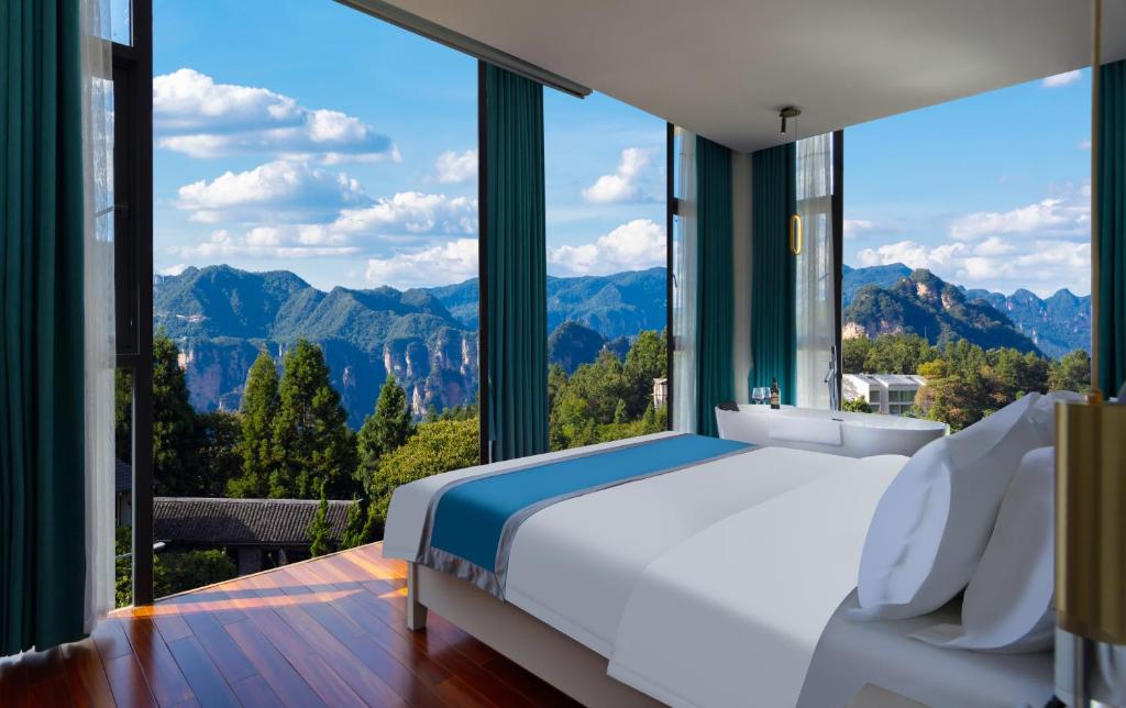 a bedroom with a large window with a bed and mountains at Zhangjiajie Cloudscape Lodge-English Services-Near the Ticket Gate in Zhangjiajie
