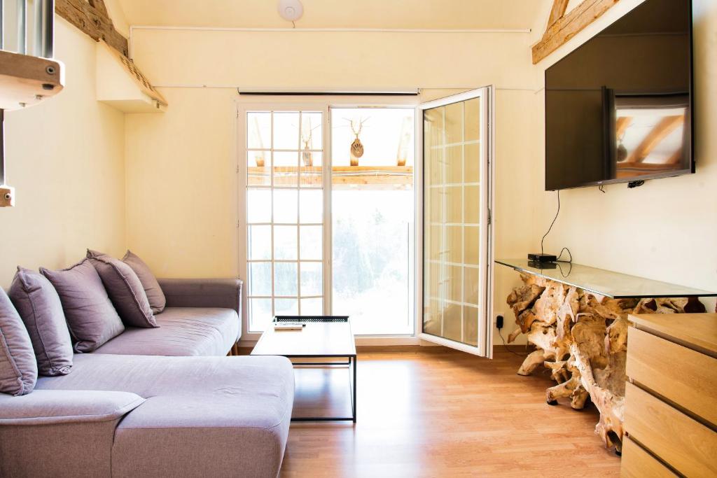 ein Wohnzimmer mit Sofa und Fernseher in der Unterkunft Duplex dans grande ferme rénovée in Divonne-les-Bains