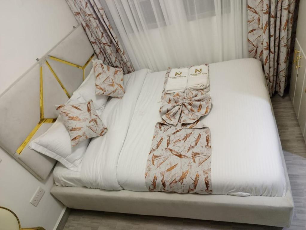 a white bed with pillows on it in a room at Stylish Studio Retreat- Inside Kunste Hotel in Nakuru