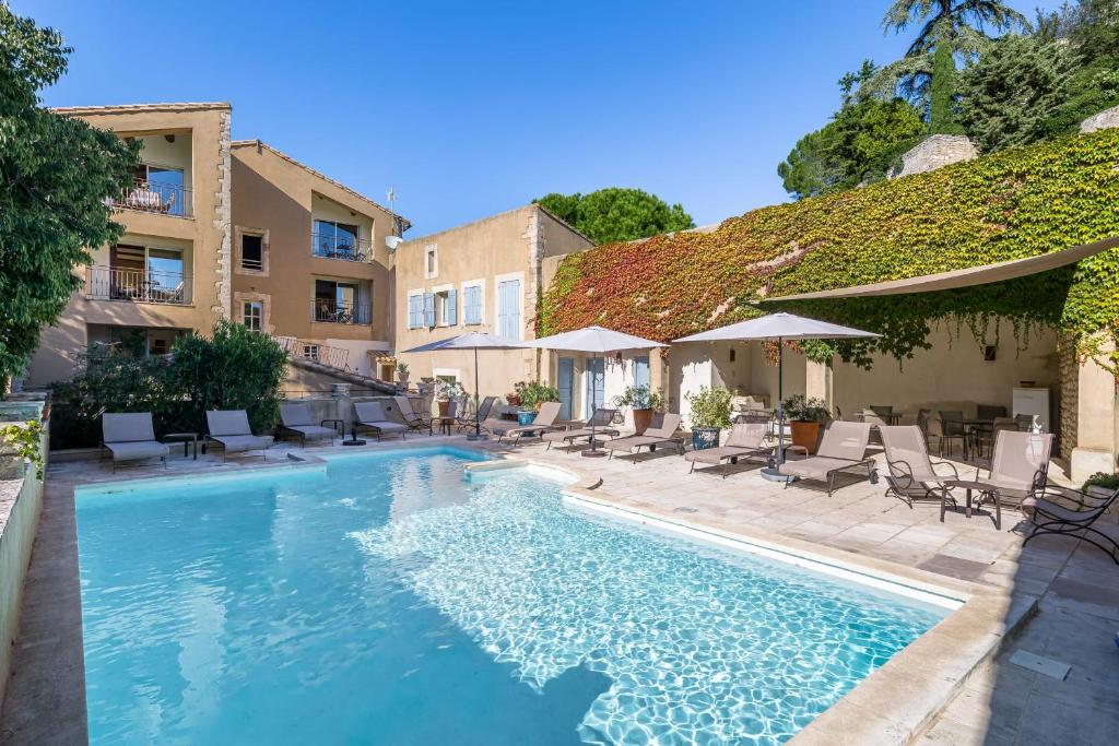 a pool with chairs and umbrellas next to a building at Le Major in Cadenet