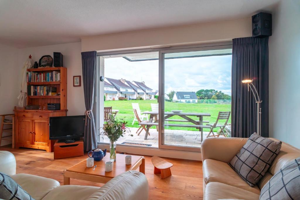 a living room with a couch and a television and a table at Ciel Etoilé - Proche de la mer in Locmariaquer