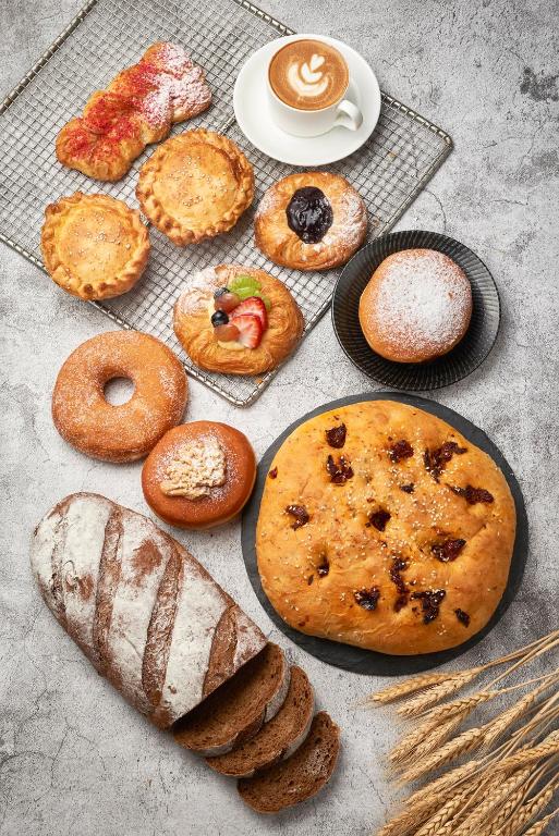 A styled spread of breads, pastries and coffee on a pale tabletop.