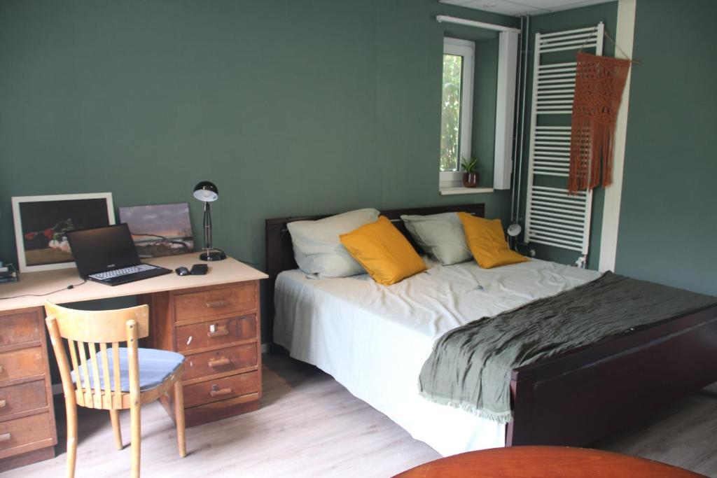 a bedroom with a bed and a desk with a laptop at B&B Even Heukelom - Kamer met Tuin in Afferden