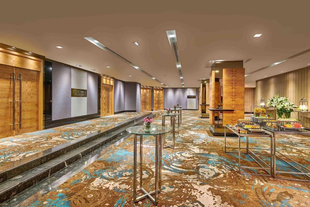 A broad carpeted hotel event or lobby space is prepared with tables and refreshments.