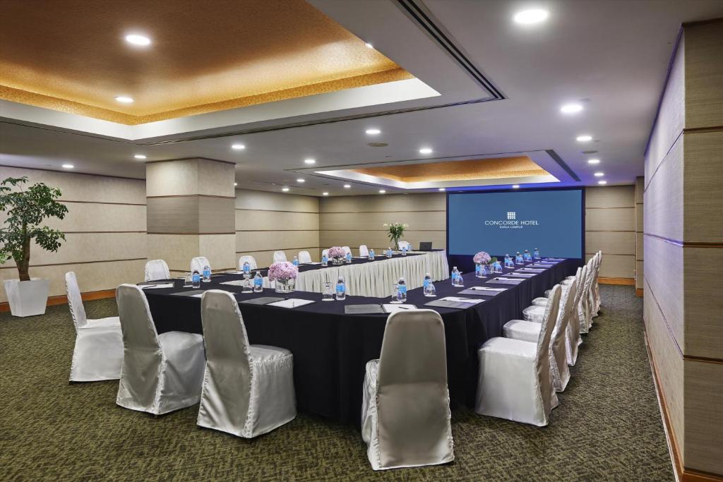 A private event room is arranged in a long U-shaped table layout around a central screen.