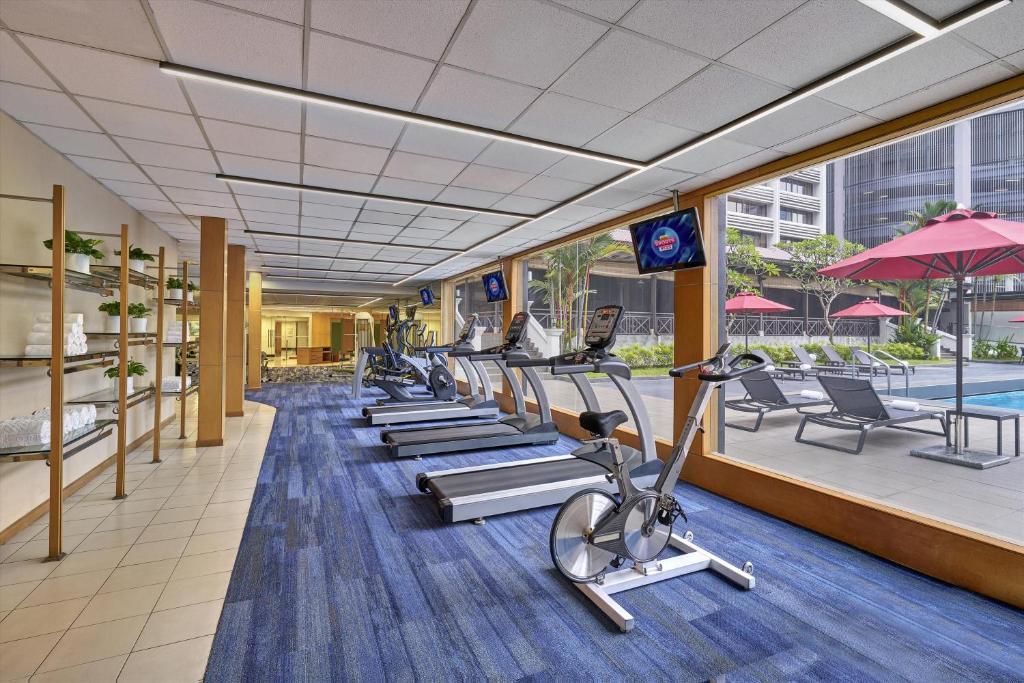 A bright fitness room overlooks the pool terrace through floor-to-ceiling windows.