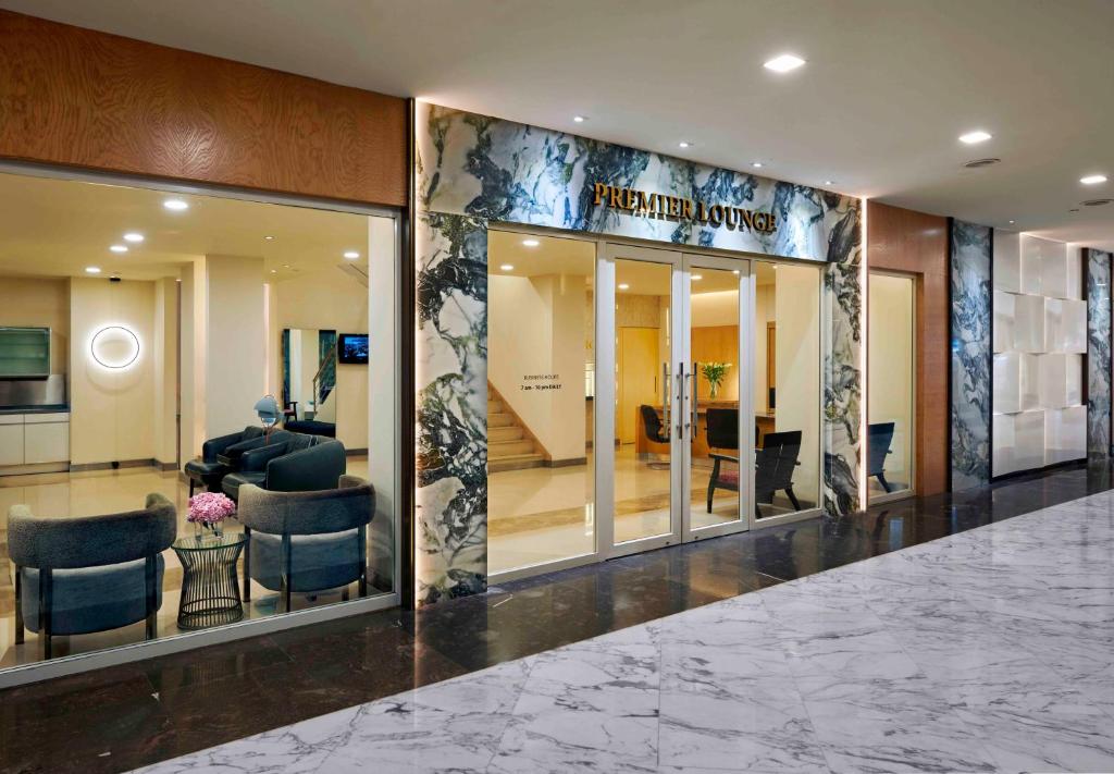 A marble corridor leading to a glass-fronted Premier Lounge.