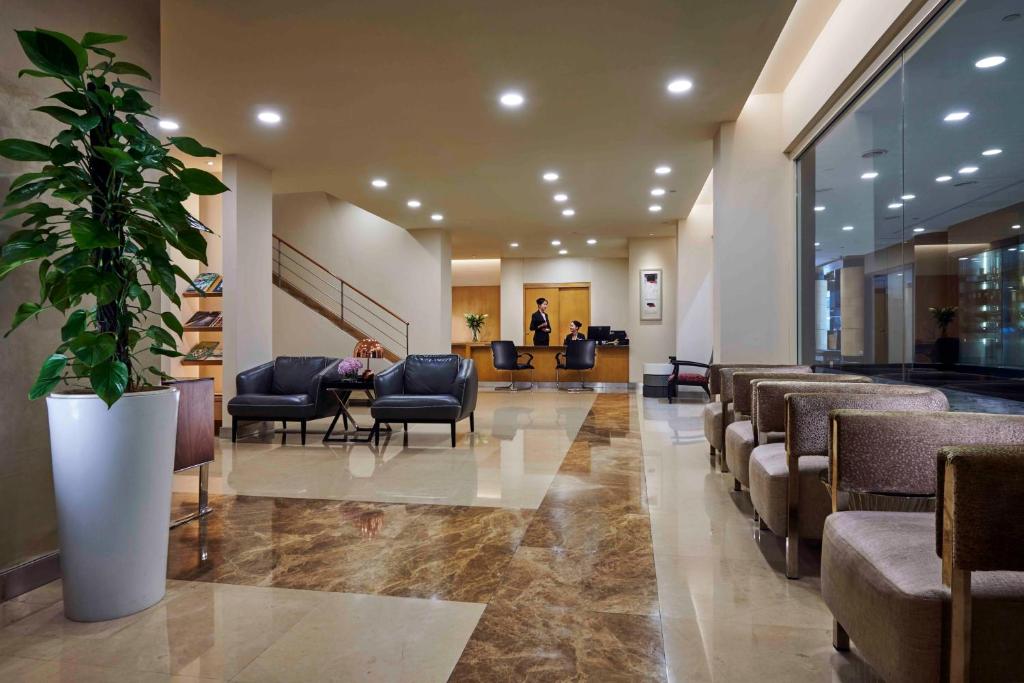 A polished hotel waiting area with lounge seating and a reception desk.