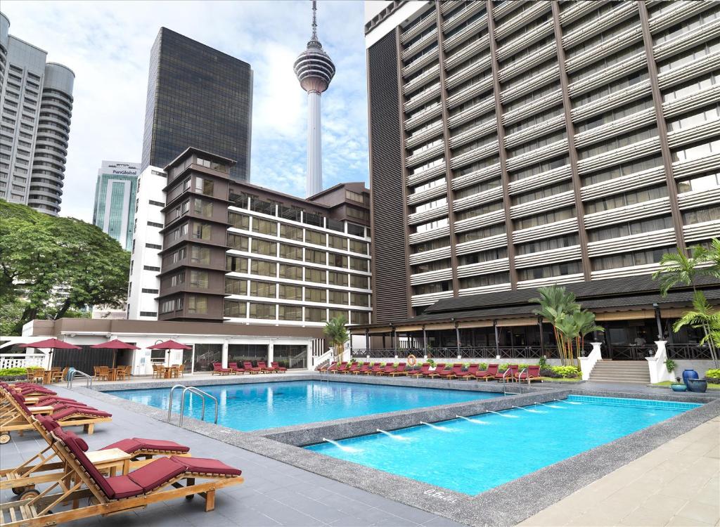 A large outdoor pool terrace with loungers and a Kuala Lumpur tower view.