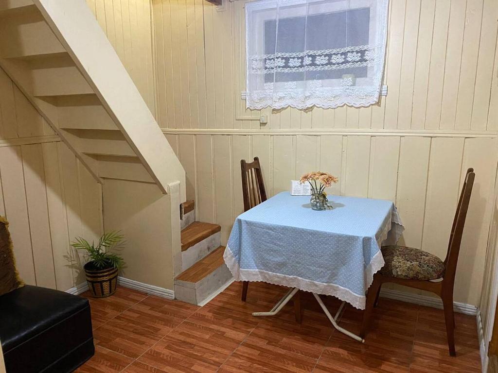 a table and chairs in a room with a staircase at Cabañas Casa Blanca in Valdivia