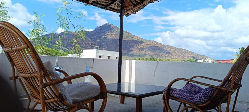 a patio with two chairs and a table and an umbrella at Beverly Dinesh Homestay in Tiruvannāmalai