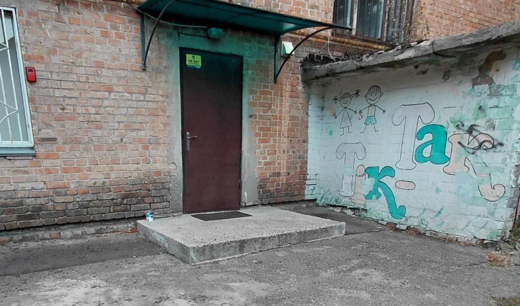 a brick building with a door with graffiti on it at apartments with shared bathroom in Cherkasy