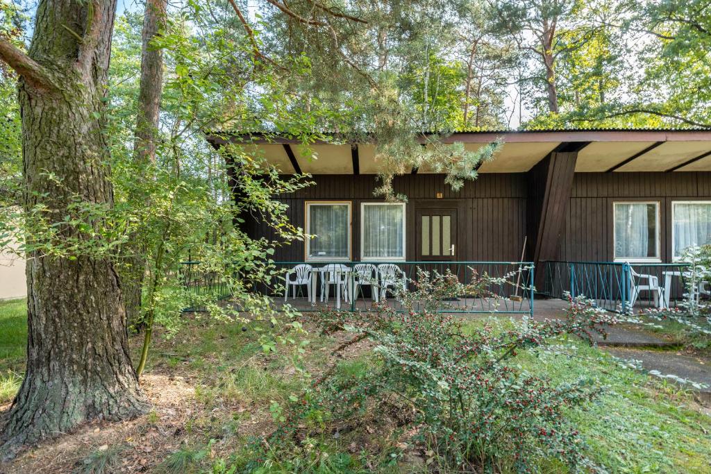 ein Haus mit Tischen und Stühlen davor in der Unterkunft Bungalow 8 - Kimbucht in Reichendorf