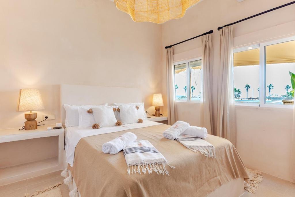 una camera da letto bianca con un grande letto con asciugamani sopra di Templo Sotogrande a Sotogrande