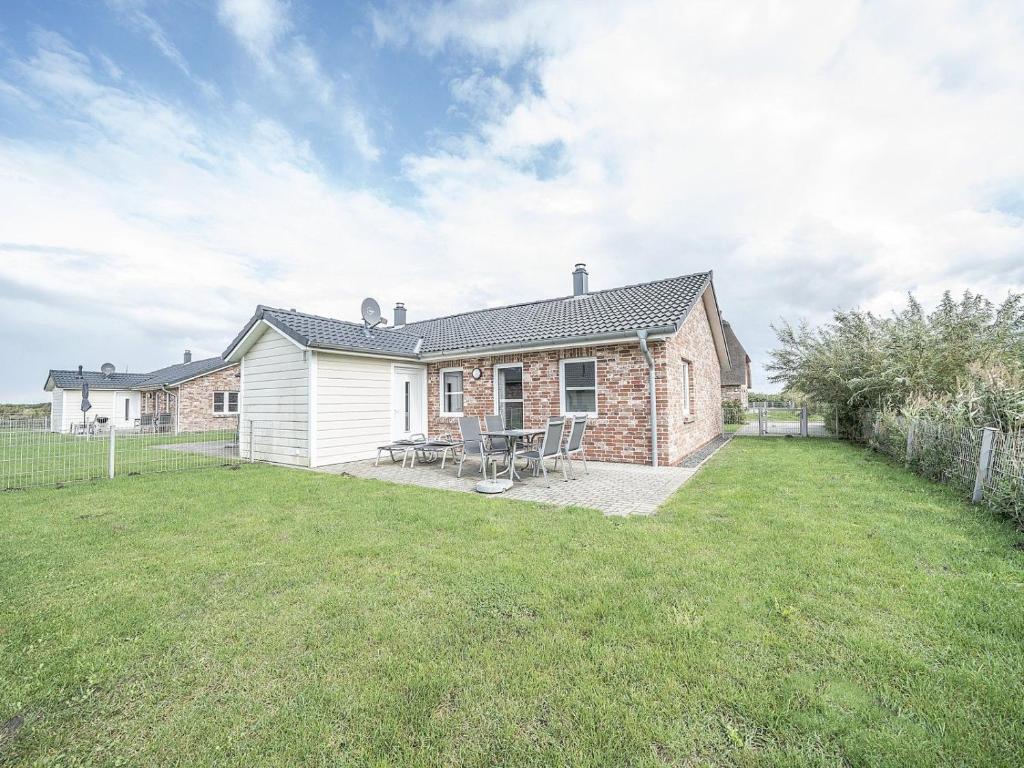 a brick house with a table and chairs in a yard at Moderne Doppelhaushälfte - perfekt zu zweit in Dagebüll