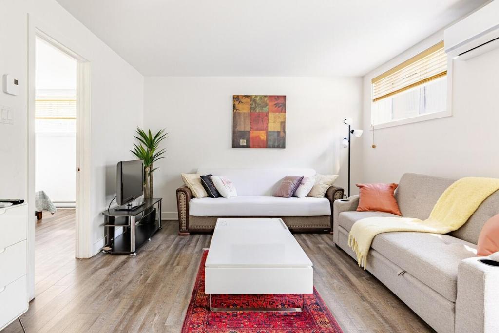 a living room with two couches and a tv at Logement neuf, spacieux in Longueuil