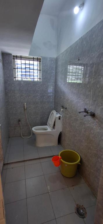 a bathroom with a toilet and a shower and a bucket at B Pool Villa in Yercaud