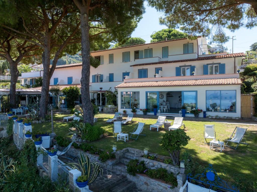 a building with a yard with chairs and trees at Hotel Sant'Andrea in Marciana