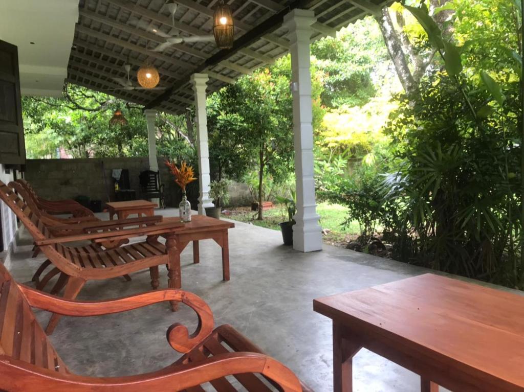 a patio with wooden tables and chairs and trees at Kadol Villa in Unawatuna