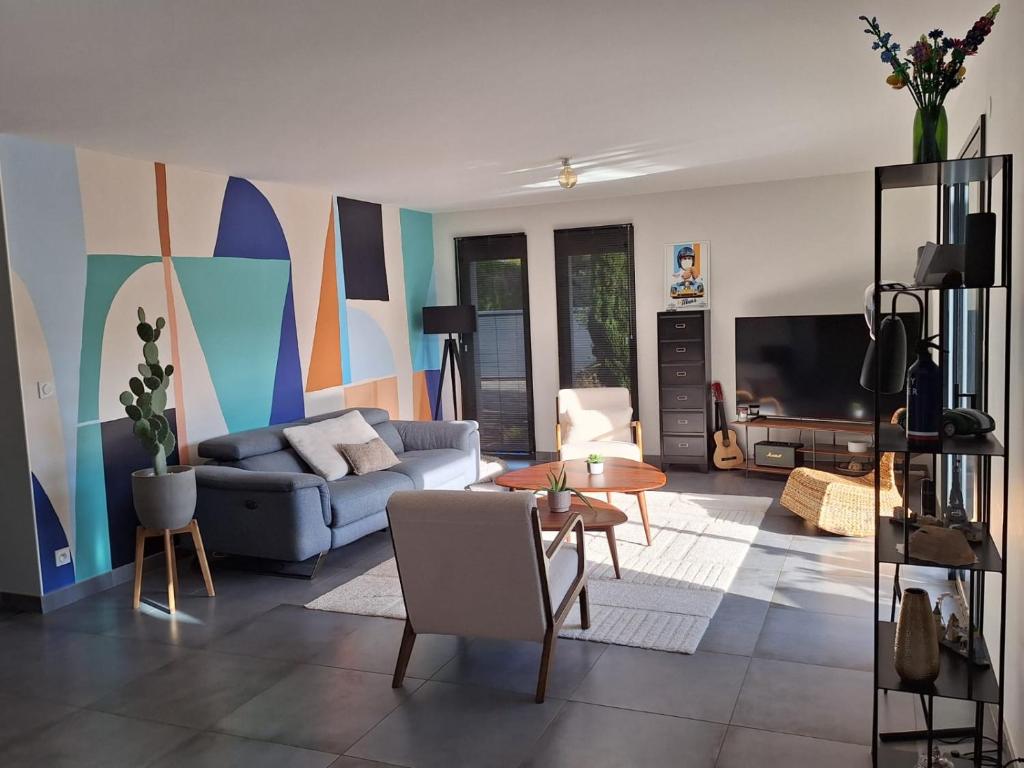 a living room with a couch and a tv at Parenthèse contemporaine - Élégance et nature in Parigné-lʼÉvêque