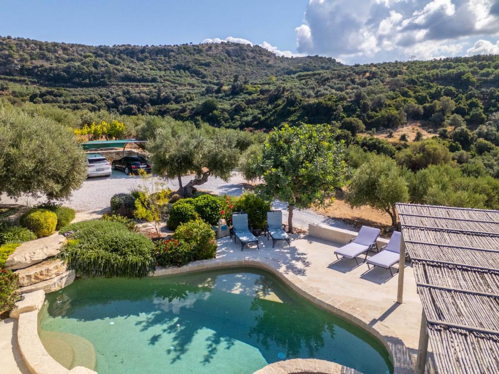 una vista sul soffitto di una piscina con sedie e alberi di Villa Lucy by PosarelliVillas a Plataniás