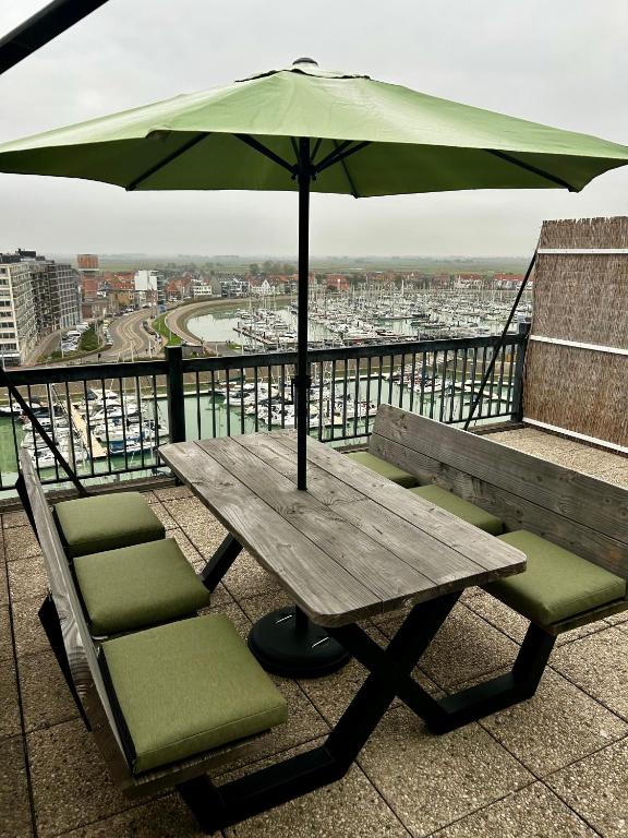a wooden table with chairs and an umbrella on a balcony at Penthouse Vakantielust in Blankenberge