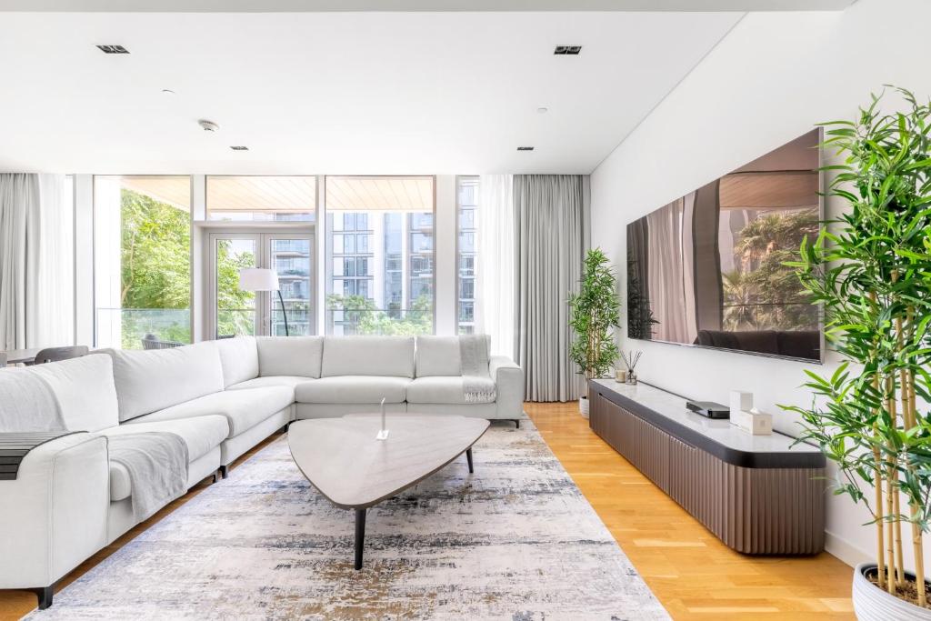 een woonkamer met een witte bank en een tv bij Island Paradise - Stylish 1BR on Bluewaters Island in Dubai