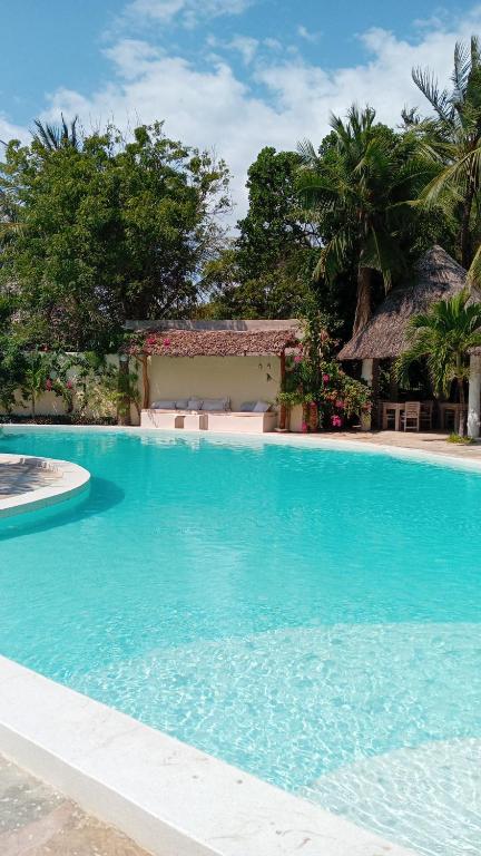 a large swimming pool with blue water in a resort at Villa Nyumba Hatimaye in Watamu