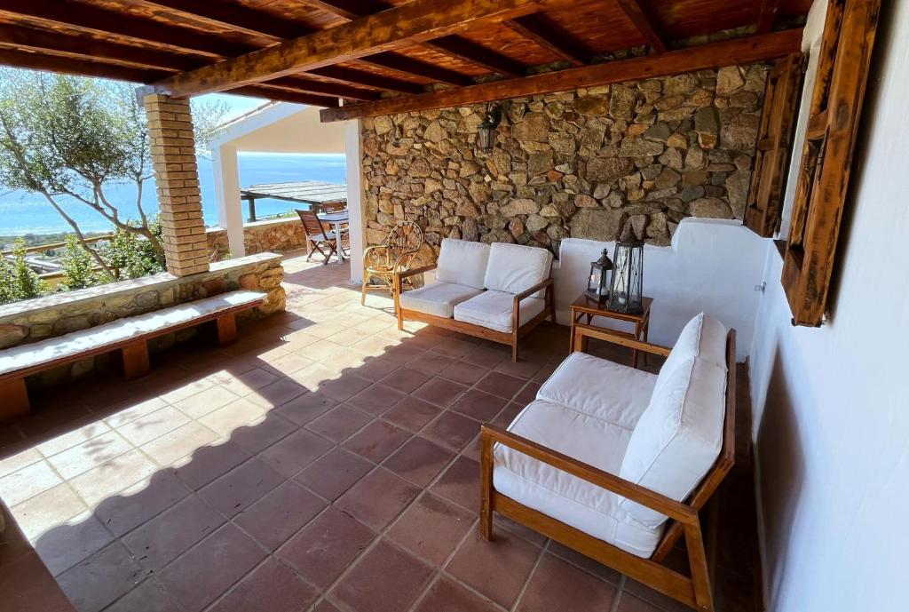 a patio with white chairs and a stone wall at Domus Sole in Campu Longu