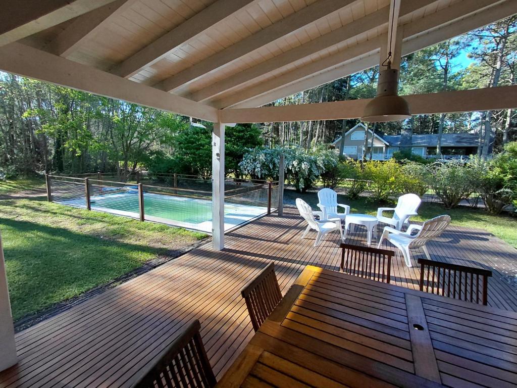 a wooden deck with white chairs and a table at Casa grande Carilo in Carilo