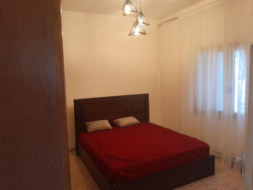 a bedroom with a bed with red sheets and a window at Weibdeh 3b furnished rooms in Amman