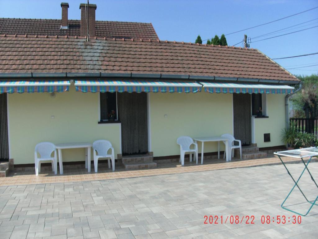 a patio with two tables and chairs and a building at Dorina Vendégház in Hajdúszoboszló