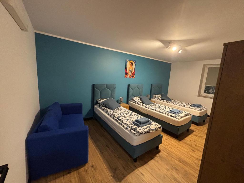 a room with three beds and a blue couch at Nowy Zakątek in Kobyla Góra