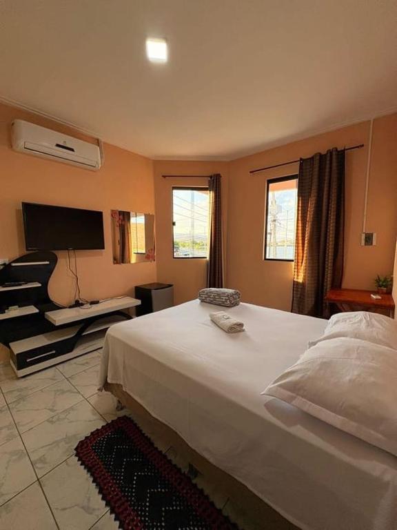 Un dormitorio con una gran cama blanca y un televisor de pantalla plana. en Pousada Calçadão, en Ipueiras