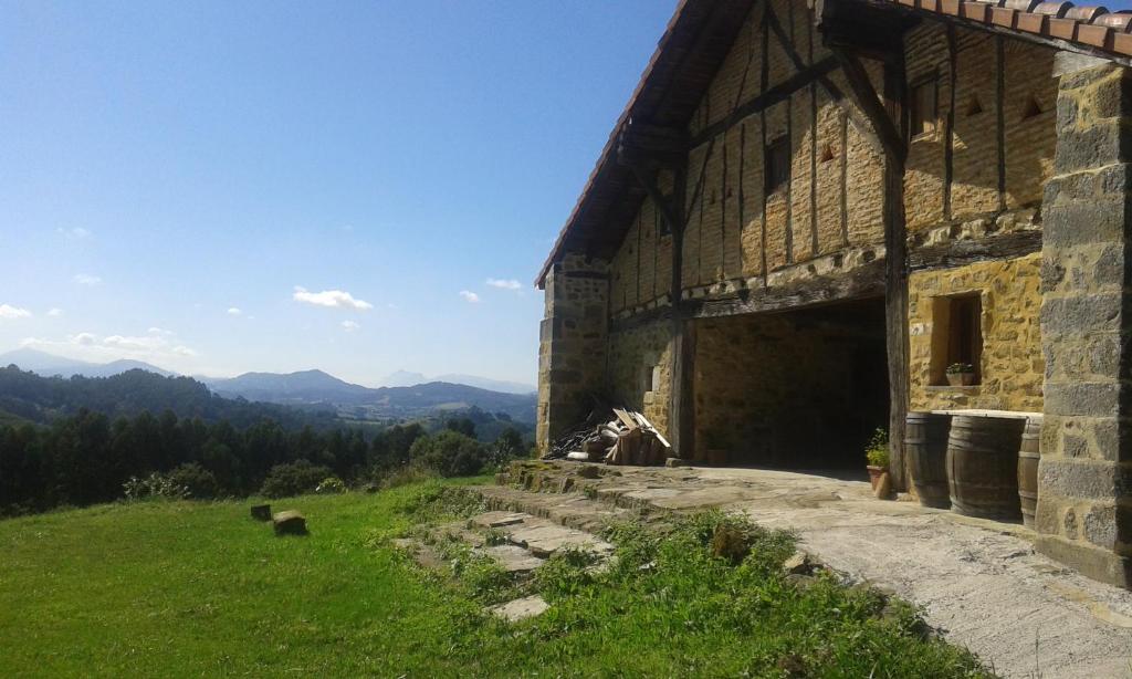 a barn on a hill with mountains in the background at Alojamiento Rural Goierri in Barrika