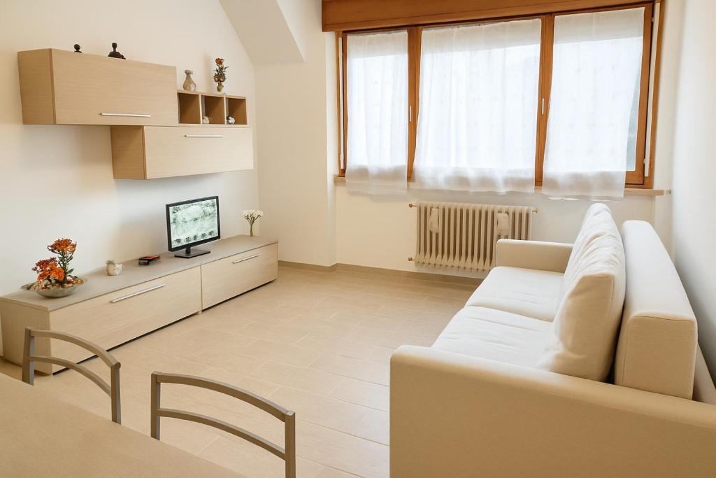 a living room with a white couch and a television at Wald Haus Tarvisio in Tarvisio