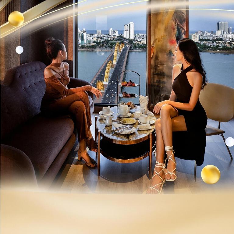 Dos mujeres sentadas en una habitación con una mesa. en MOONLIGHT Hotel & Suites - High floor, River view, Dragon Bridge view, City view, en Da Nang
