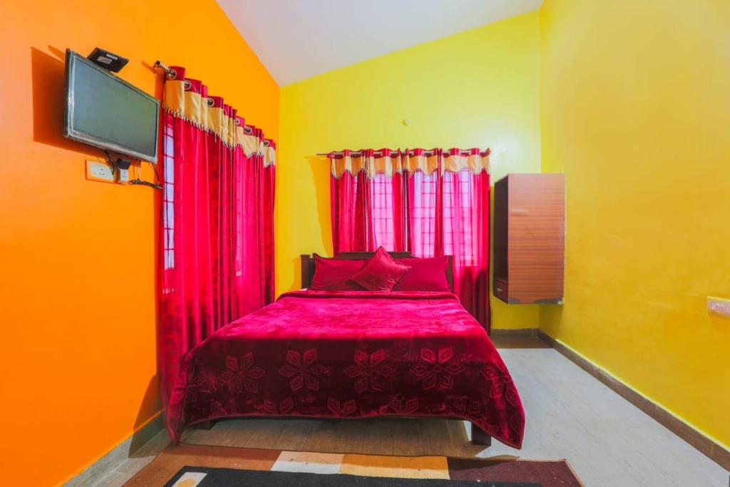 Uma cama vermelha em um quarto amarelo com uma TV. em Butterfly homestay em Ooty