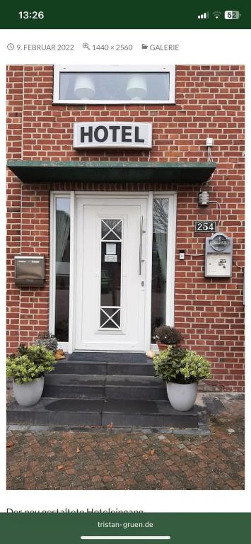 a hotel with a door and two plants in front of it at Hotel Tristan Grün in Rheine