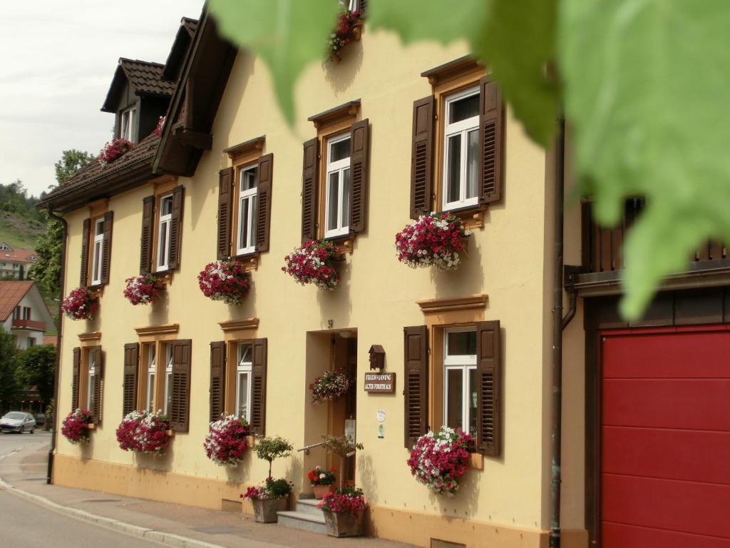 un edificio amarillo con flores en las ventanas en Altes Forsthaus - Fewo Bianca, en Bad Peterstal-Griesbach