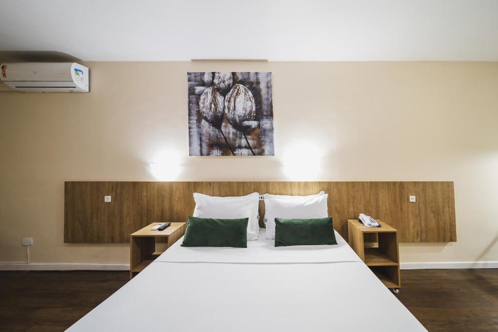 a bedroom with a large white bed with two tables at Hotel Nacional Inn Curitiba Torres in Curitiba