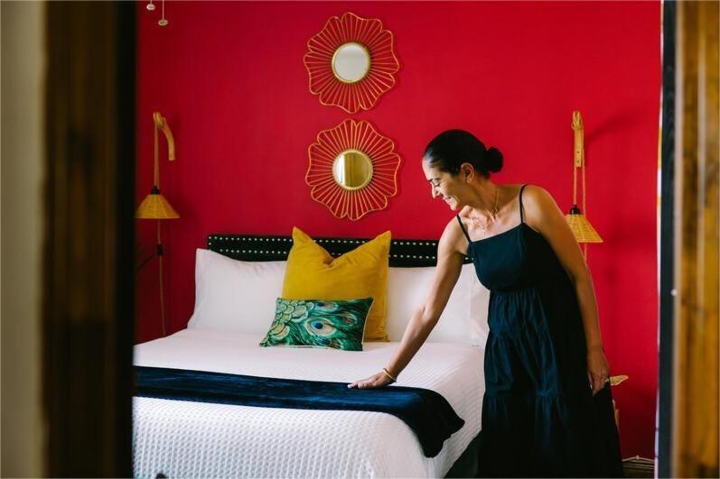 a woman in a black dress standing next to a bed at test 4 in Jāmb