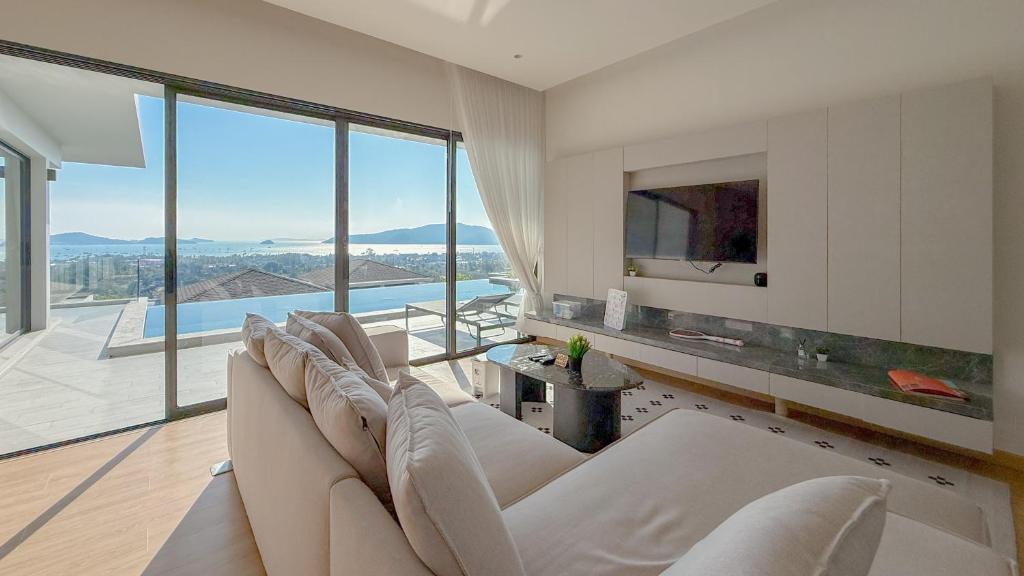 a living room with a white couch and a large window at The Salin Seaview Villas in Kata Beach