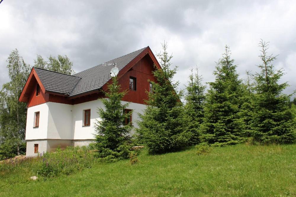 una casa roja y blanca en una colina con árboles en Chata Béďa, en Bedřichov
