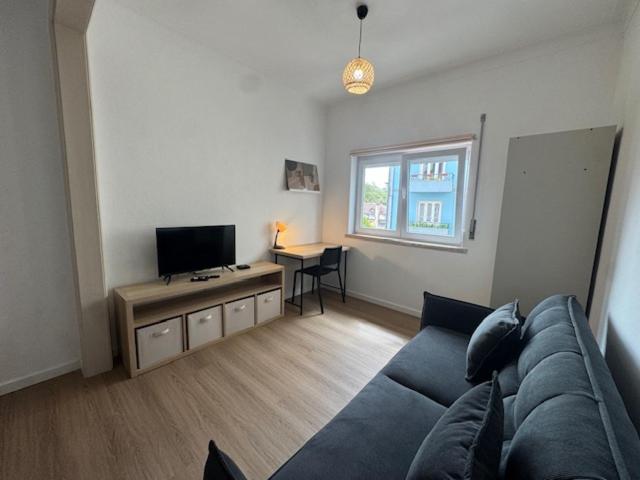 een woonkamer met een blauwe bank en een televisie bij Apartamento Central Rainha in Caldas da Rainha