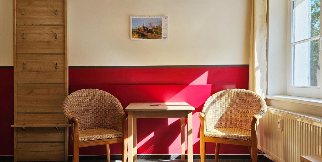 two chairs and a table in a room with a red wall at Mollibahnhof - Heiligendamm Mollibahnhof Heiligendamm DZ 04 in Heiligendamm